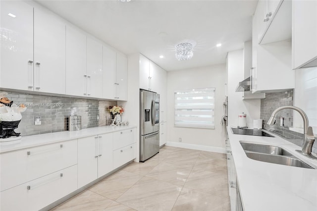 kitchen featuring baseboards, a sink, white cabinets, and stainless steel fridge with ice dispenser