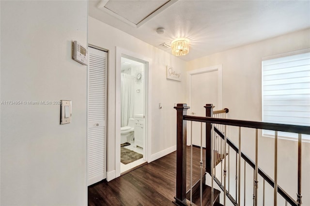 corridor with baseboards, dark wood-style flooring, and an upstairs landing