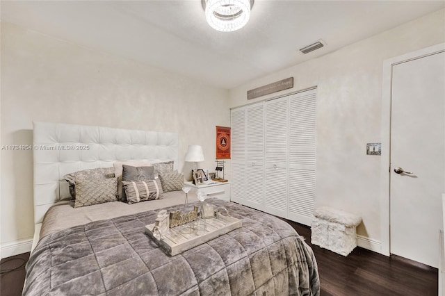 bedroom featuring a closet, baseboards, wood finished floors, and visible vents