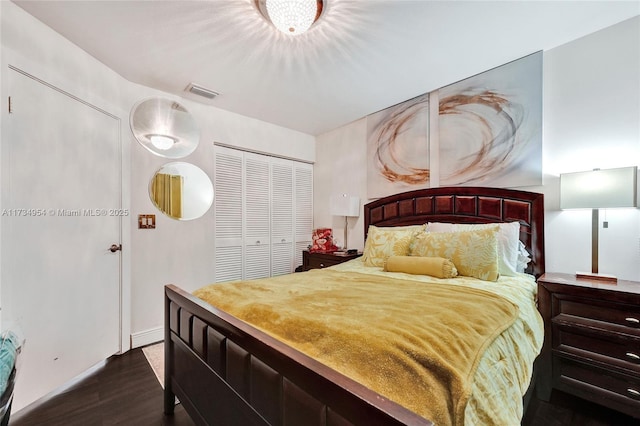 bedroom with dark wood-type flooring, baseboards, visible vents, and a closet