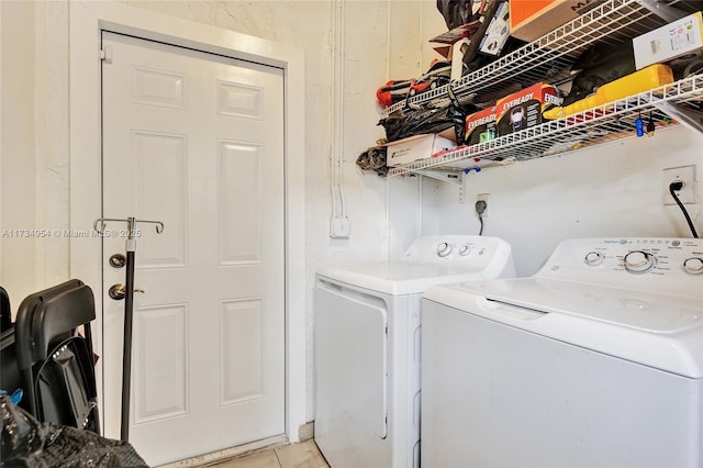 laundry area with washer and clothes dryer and light tile patterned floors