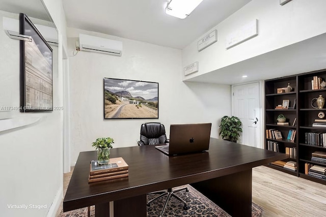 home office featuring light wood finished floors and a wall mounted air conditioner