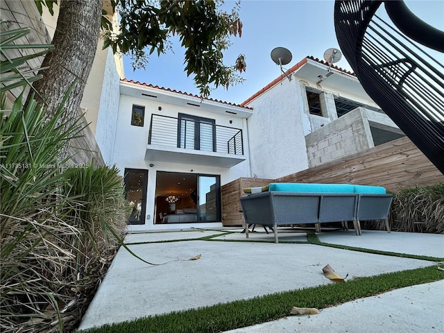 rear view of house with a balcony and an outdoor living space