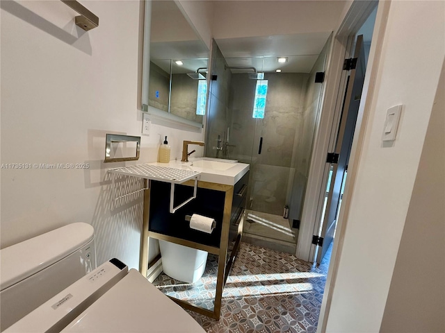 bathroom featuring a shower with door, vanity, and toilet