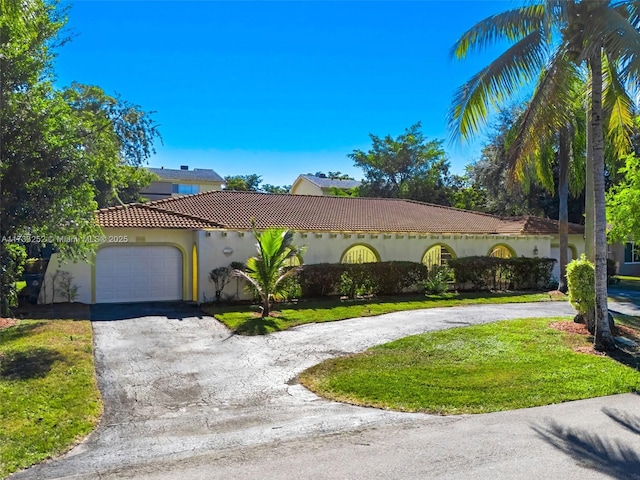 mediterranean / spanish house featuring a garage and a front yard