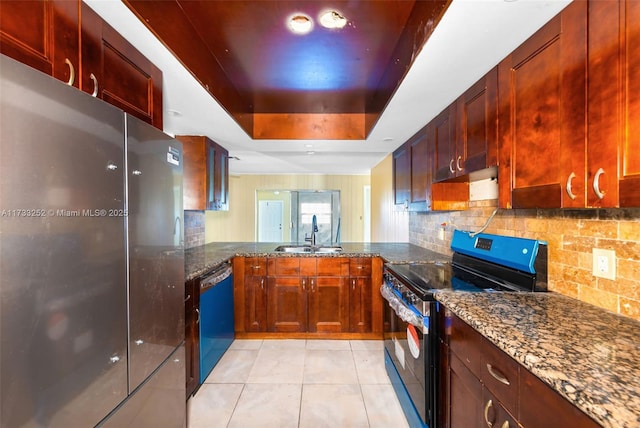 kitchen featuring stainless steel appliances, a raised ceiling, sink, and dark stone countertops