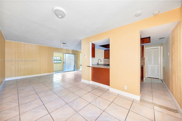 spare room with sink, light tile patterned floors, and wood walls