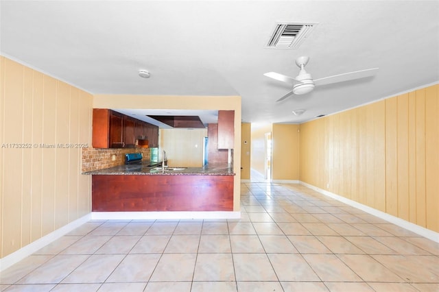 kitchen featuring sink, light tile patterned floors, kitchen peninsula, ceiling fan, and dark stone counters