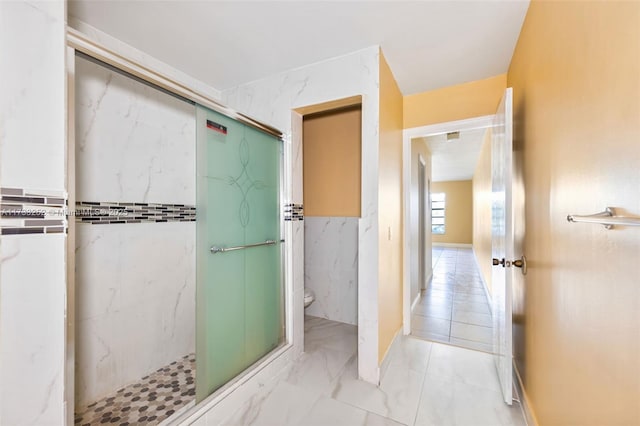 bathroom with a shower with door and toilet