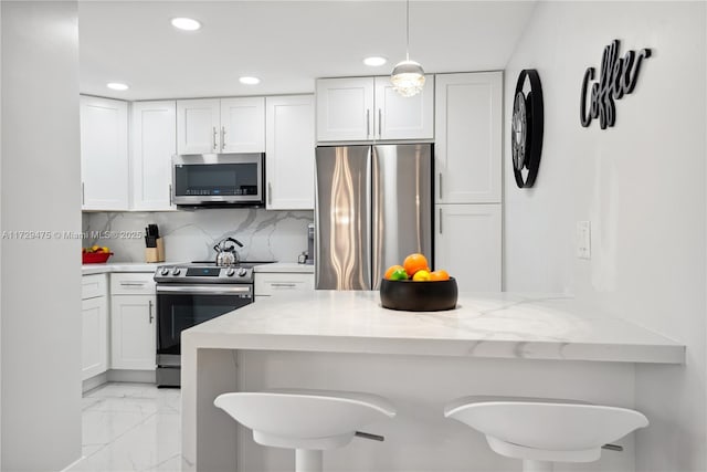 kitchen with white cabinetry, light stone counters, stainless steel appliances, and a breakfast bar