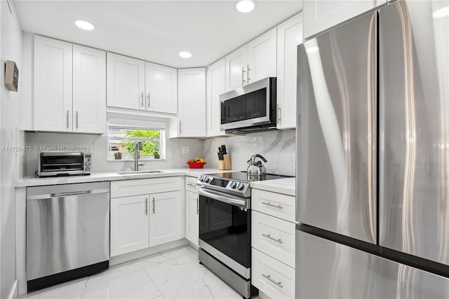 kitchen featuring white cabinetry, appliances with stainless steel finishes, sink, and backsplash