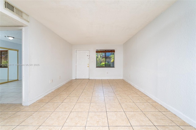 tiled spare room featuring a textured ceiling