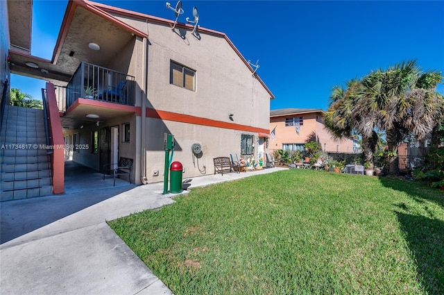 rear view of house featuring a patio, a balcony, and a yard