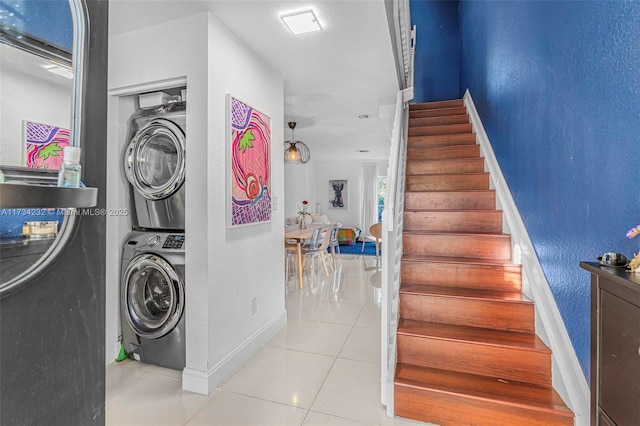 stairs featuring stacked washing maching and dryer and tile patterned floors