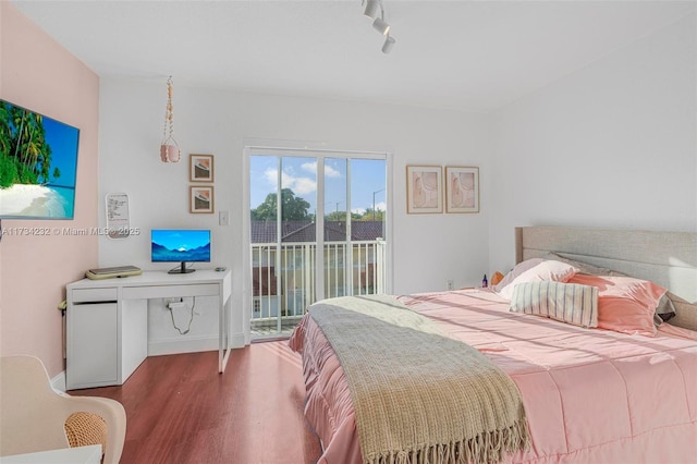 bedroom featuring track lighting, hardwood / wood-style floors, and access to outside