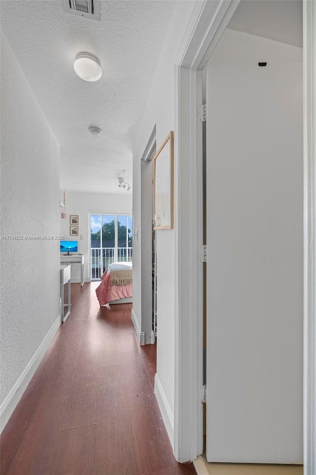 corridor with wood-type flooring and a textured ceiling