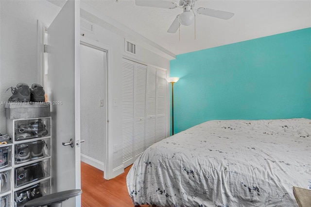 bedroom with wood-type flooring, ceiling fan, and a closet