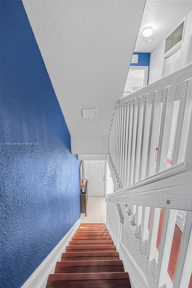 staircase with a textured ceiling