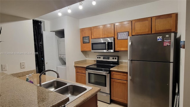 kitchen with sink, stainless steel appliances, and stacked washer and clothes dryer