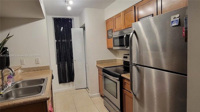 kitchen featuring stainless steel appliances, light tile patterned flooring, and sink