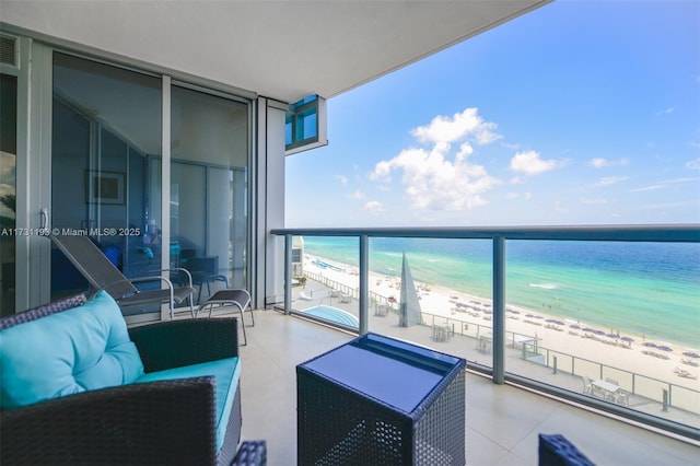 balcony with a view of the beach, a water view, and an outdoor living space