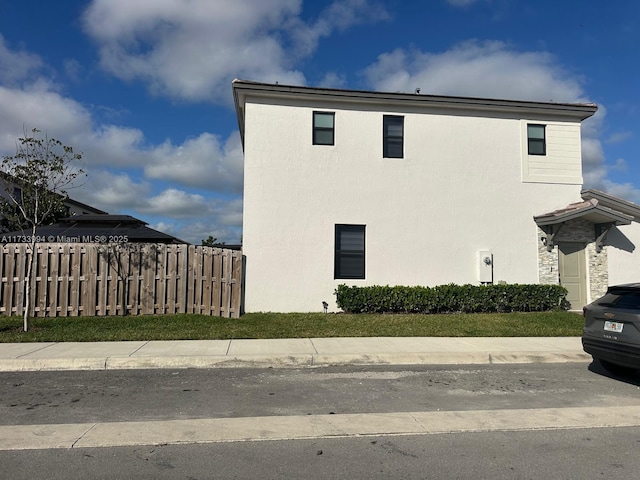 view of side of property with fence and stucco siding