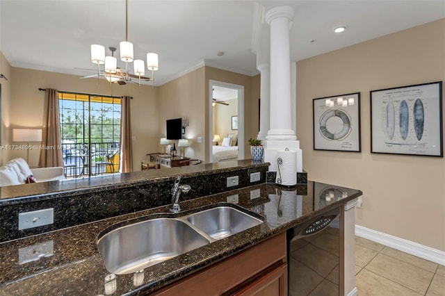 kitchen featuring sink, black dishwasher, decorative light fixtures, dark stone counters, and ornate columns