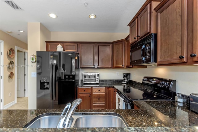 kitchen featuring light tile patterned floors, dark stone countertops, sink, and black appliances