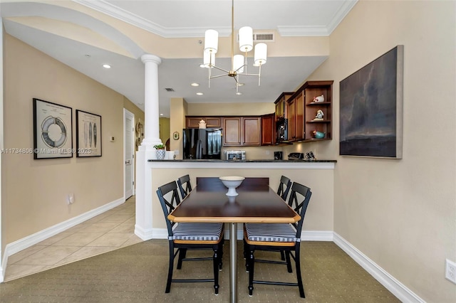 dining space with an inviting chandelier, crown molding, light tile patterned flooring, and ornate columns