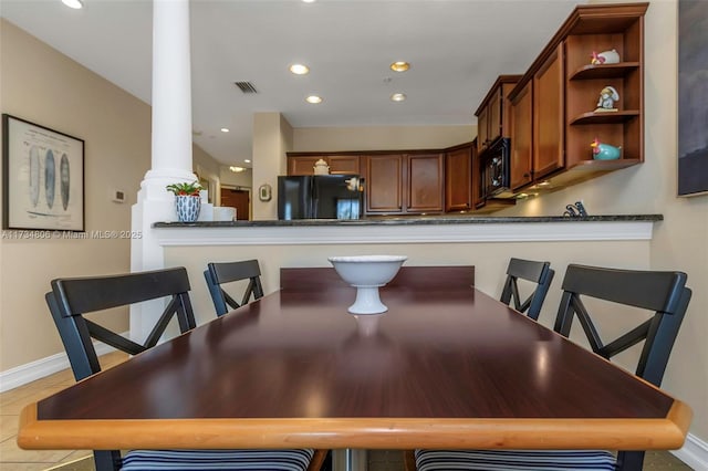 dining space with tile patterned flooring and ornate columns