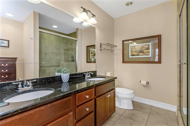 bathroom with tile patterned flooring, vanity, a shower with door, and toilet