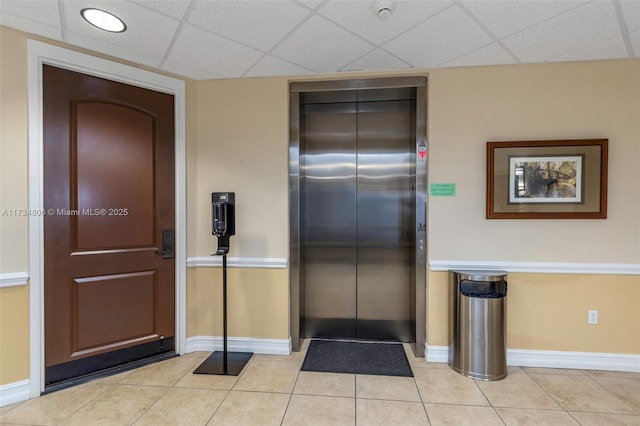 kitchen featuring light tile patterned flooring, elevator, and a drop ceiling