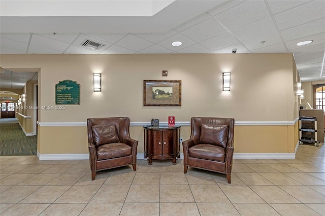 sitting room featuring a drop ceiling and light tile patterned floors