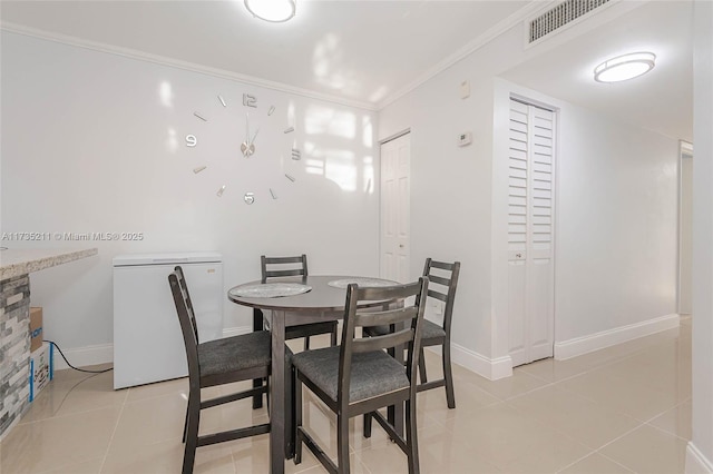 dining room featuring light tile patterned floors and crown molding