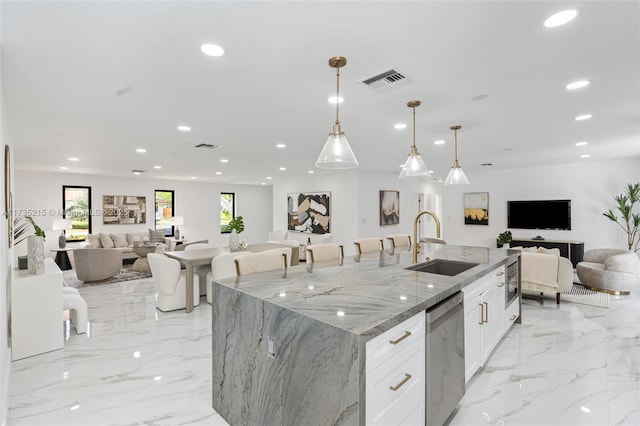 kitchen featuring sink, a kitchen island with sink, light stone countertops, white cabinets, and stainless steel dishwasher