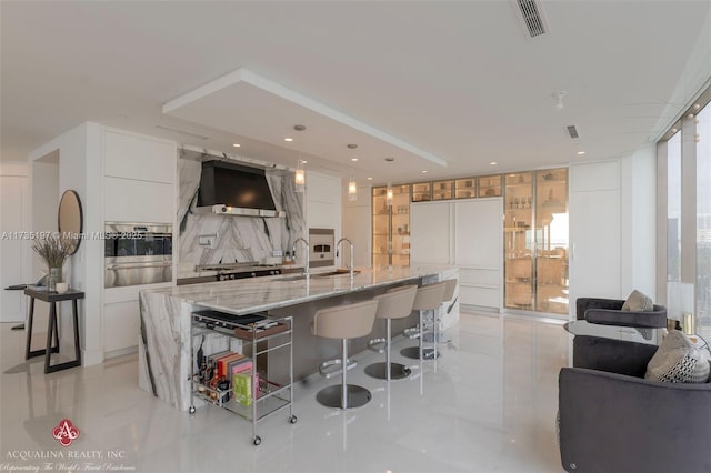 kitchen with white cabinetry, wall chimney exhaust hood, and a spacious island