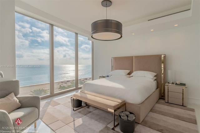 bedroom with a view of the beach, expansive windows, and a water view