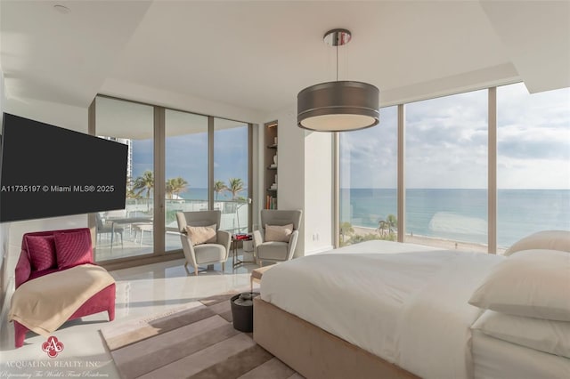 bedroom featuring access to outside, a wall of windows, and a water view