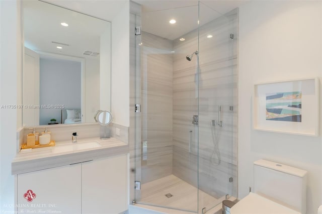 bathroom featuring vanity, a shower with shower door, and toilet