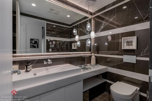 bathroom featuring vanity, tile walls, and toilet