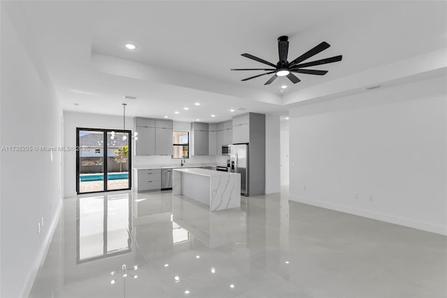 kitchen featuring appliances with stainless steel finishes, gray cabinets, a raised ceiling, a kitchen island, and pendant lighting