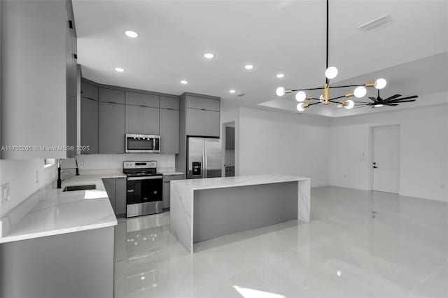 kitchen with a kitchen island, pendant lighting, sink, stainless steel appliances, and light stone countertops