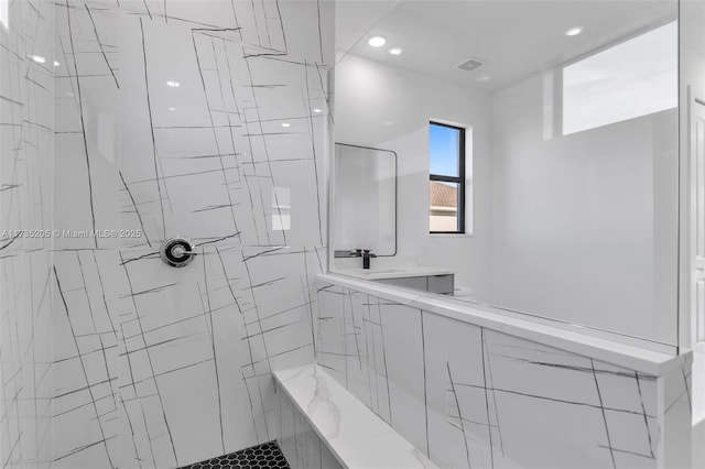 bathroom featuring a tile shower and sink