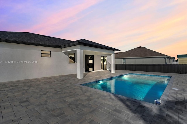 pool at dusk featuring a patio