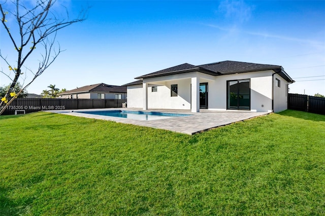 back of house with a fenced in pool, a patio, and a lawn