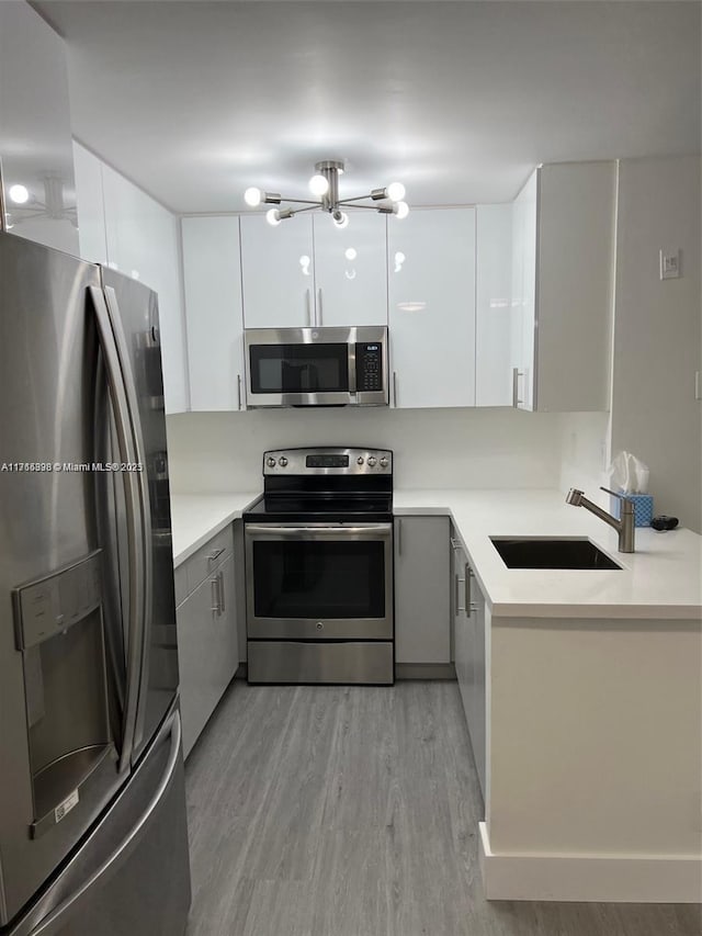 kitchen featuring stainless steel appliances, sink, white cabinets, and light hardwood / wood-style flooring