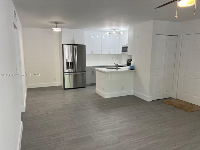 kitchen with dark hardwood / wood-style floors, sink, white cabinets, hanging light fixtures, and stainless steel appliances