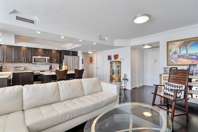 living room featuring dark hardwood / wood-style flooring, crown molding, and a raised ceiling