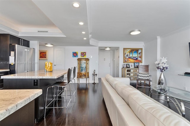 kitchen with crown molding, stainless steel fridge, dark hardwood / wood-style floors, a center island, and light stone counters