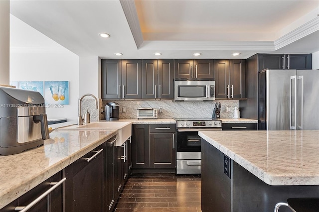 kitchen featuring dark hardwood / wood-style floors, sink, decorative backsplash, stainless steel appliances, and light stone countertops